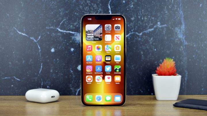 iPhone 14 Always-on An iPhone 13 Pro on a table next to Apple AirPods