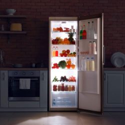 A fridge containing drinks open at night