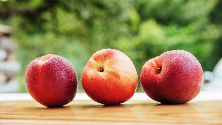 Nectarines, a variant of peaches, on a wooden board.