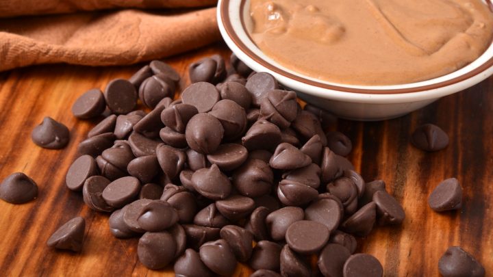 Closeup of dark chocolate chips with a bowl of peanut butter