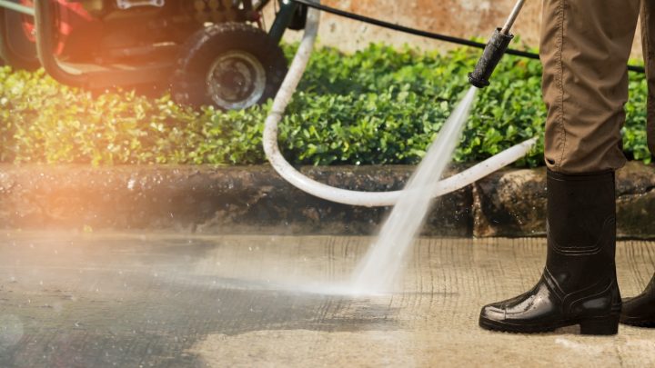 A person cleaning a driveway with a pressure washer.