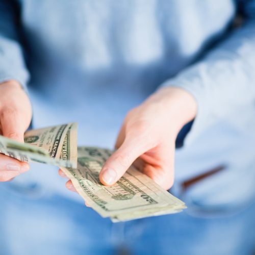 A person is shown counting out money in their hands