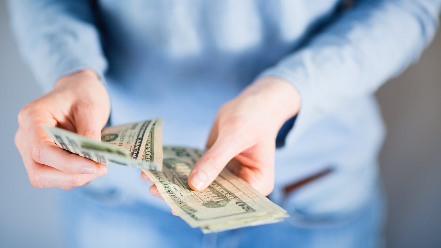 A person is shown counting out money in their hands