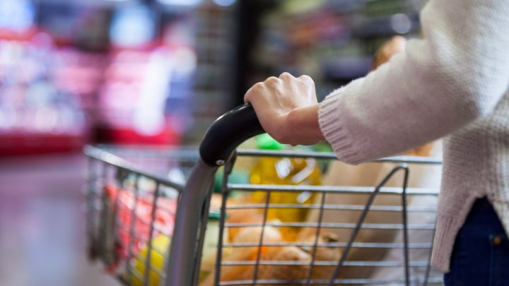 A woman is shown pushing a cart full of groceries