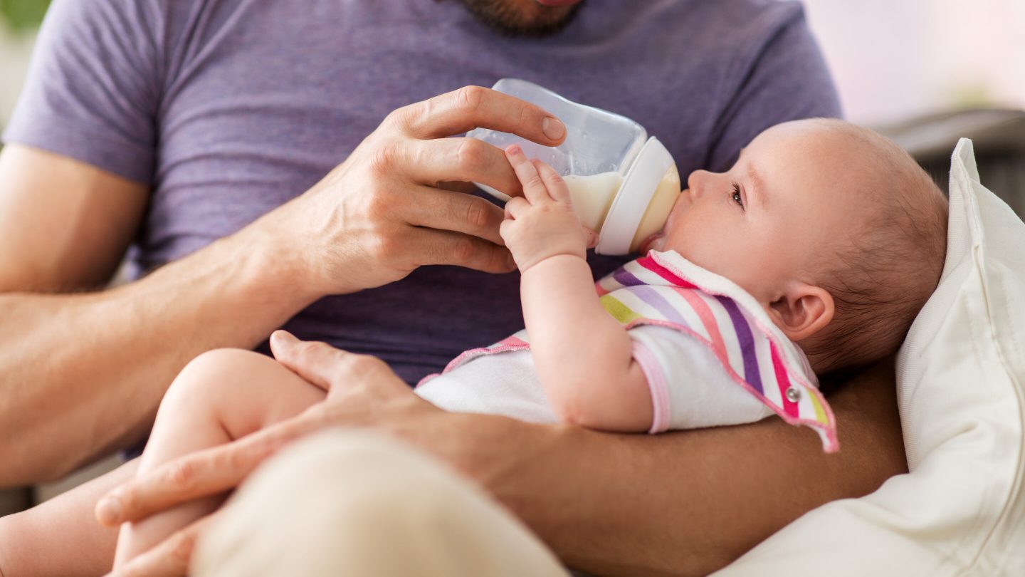 father holding and feeding a baby