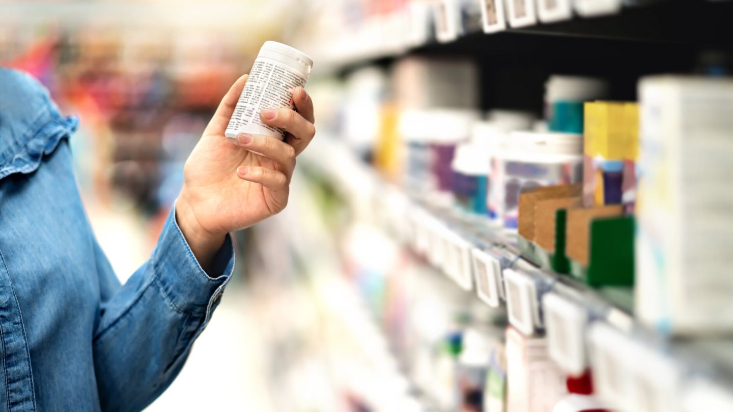 Customer in pharmacy holding medicine bottle