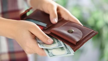 closeup of hands putting cash into wallet