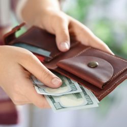 closeup of hands putting cash into wallet