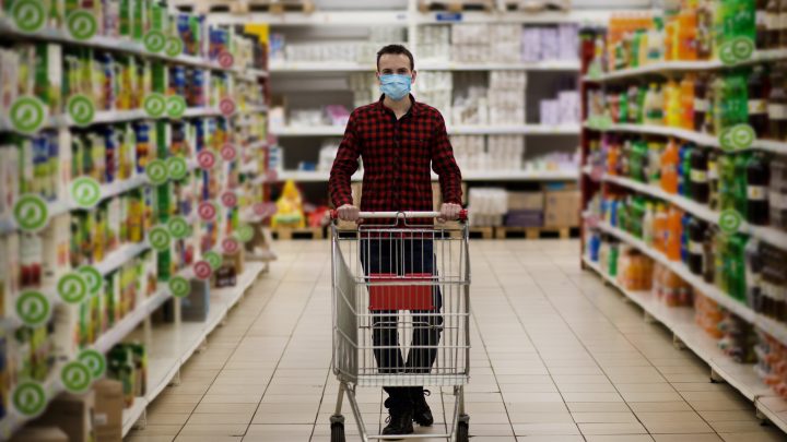 man pushes shopping cart in grocery store