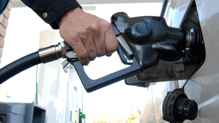 Close up of a customer's hand pumping fuel into car's gas tank