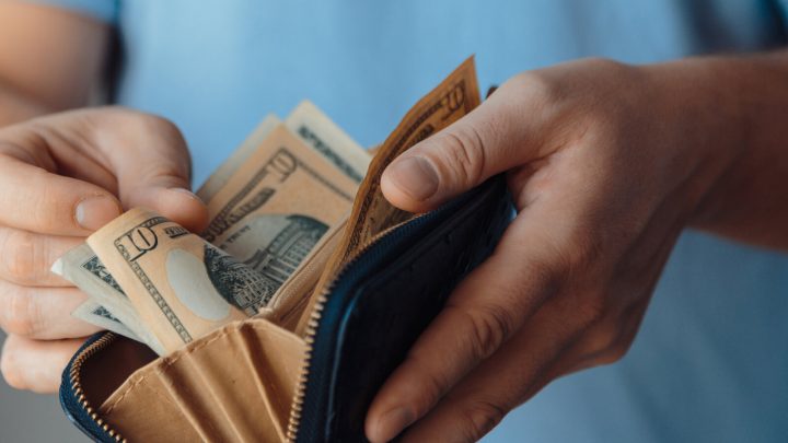 A man is shown opening a wallet full of cash.