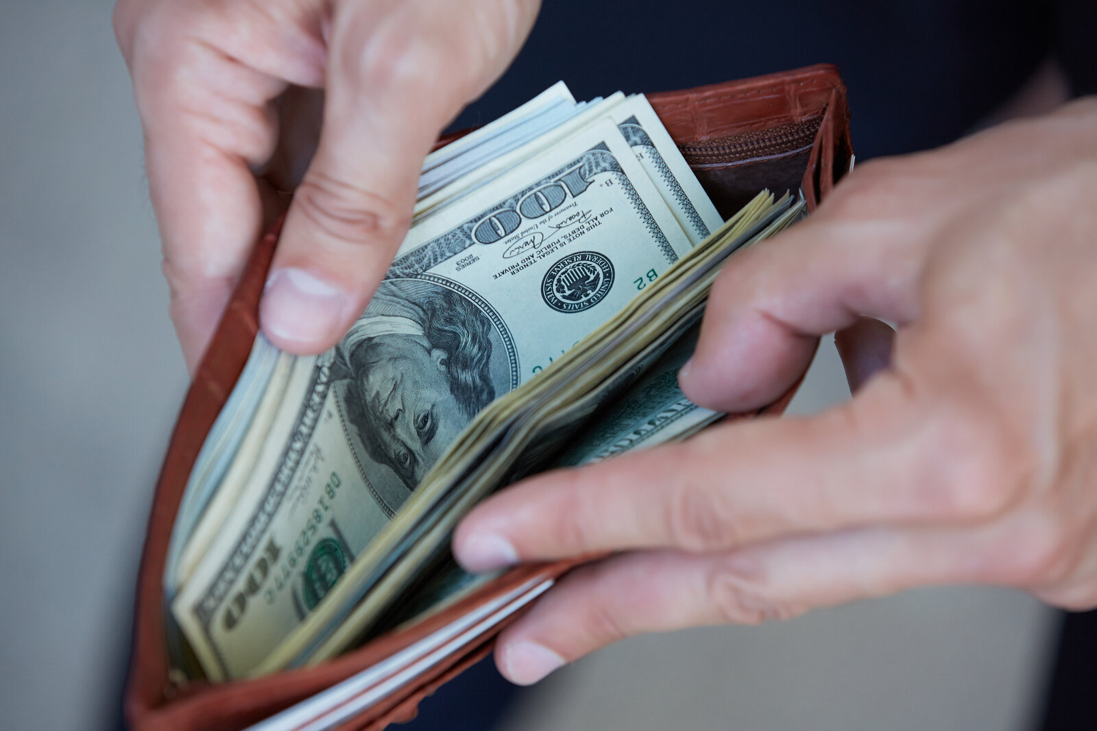 A close-up of a person opening a wallet with cash