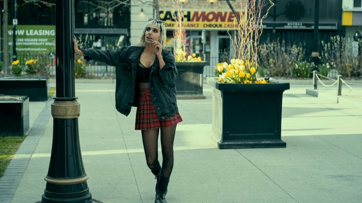 blonde woman leaning on a streetlamp