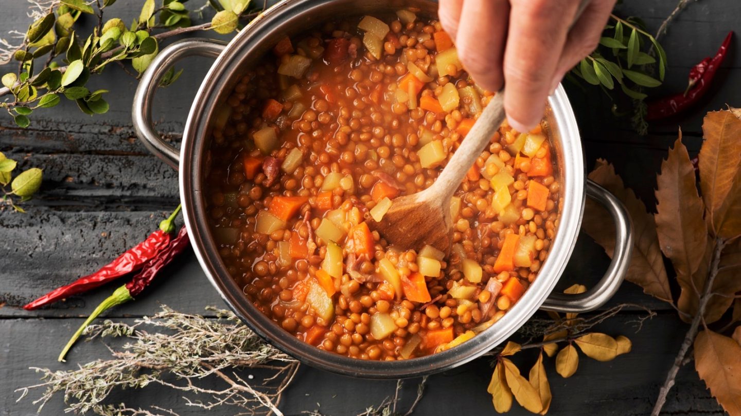 A person preparing a vegetarian lentil soup.